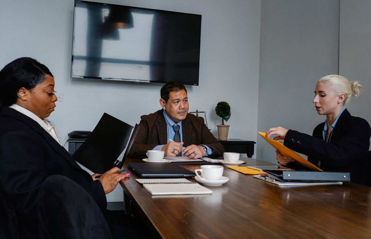 class-04 Group of multiethnic coworkers in formal wear sitting at table with documents and discussing strategy of project